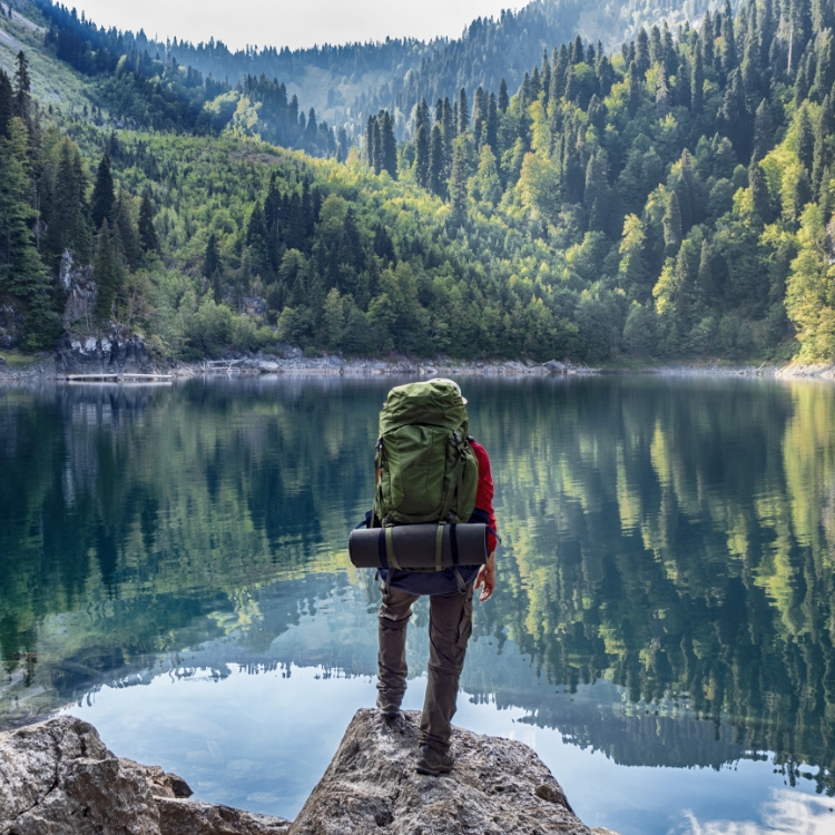 Tourist with backpack at mountain lake background