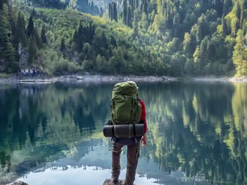 Tourist with backpack at mountain lake background