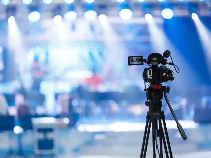 A camera pointing to a music show in the background