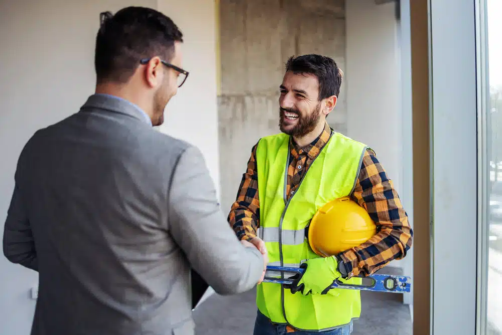 A man in a suit shaking hands with a construction worker.